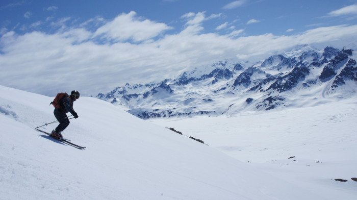 Skier prepared to ski down a tall mountain in Alaska on a corn snow skiing trip with Tordrillo Mountain Lodge.