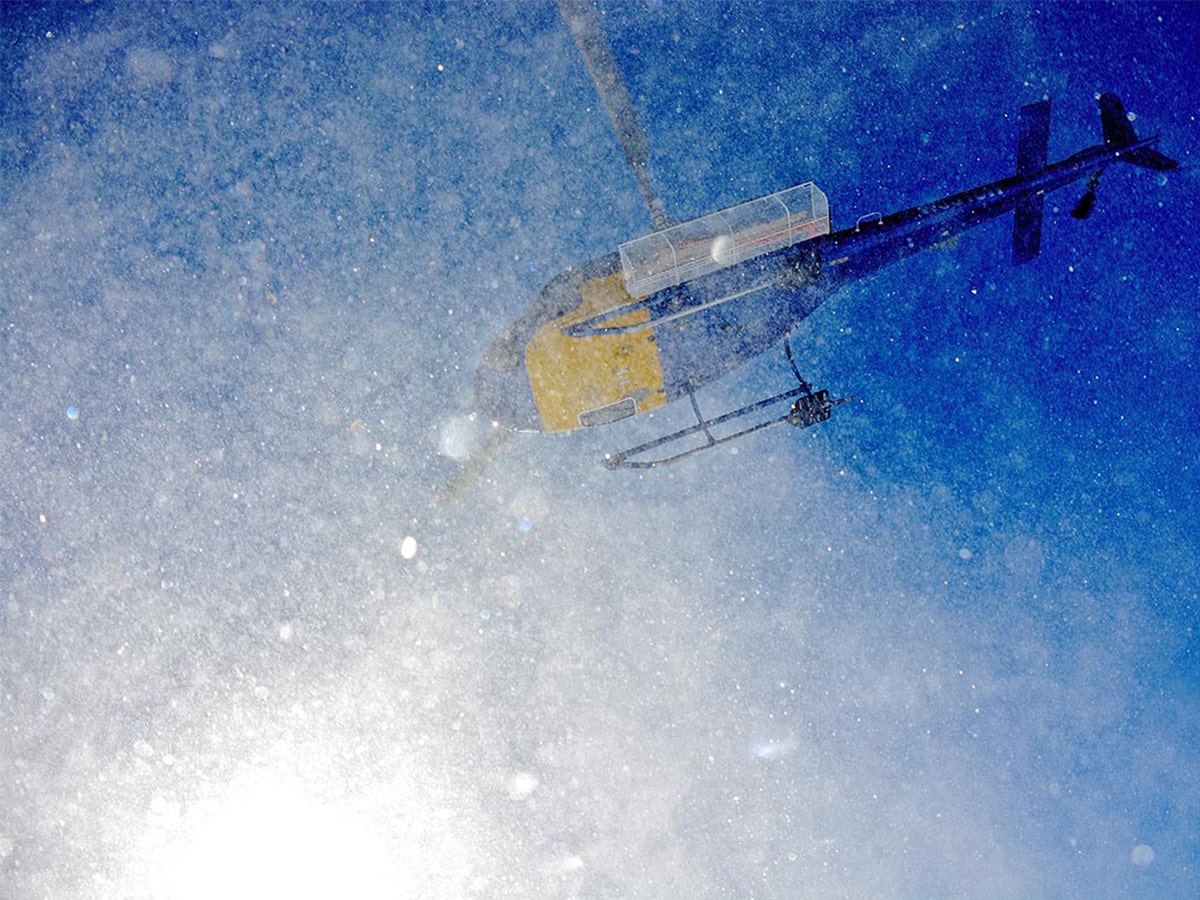 A view of the bottom of a helicopter as it lifts off into the snowy air.