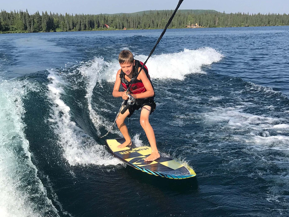 A young boy wakeboarding on Judd Lake in the summer.