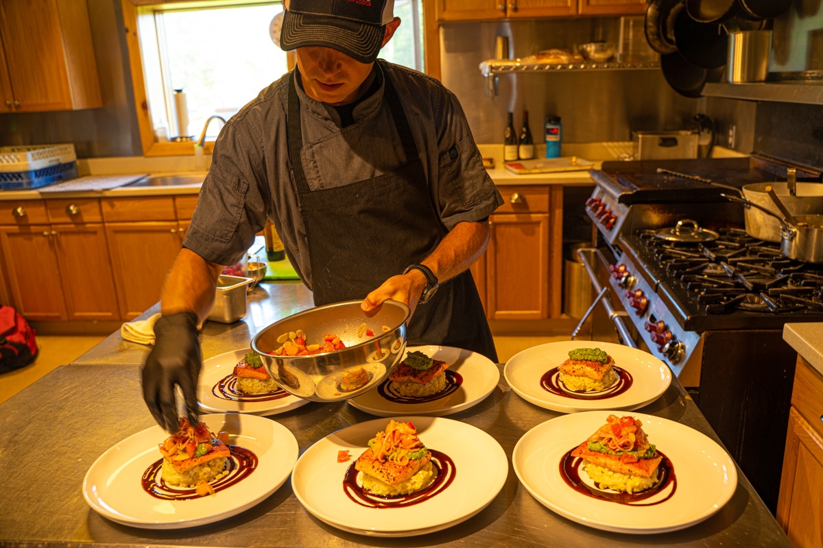 a chef plating dinners of salmon at Tordrillo Mountain Lodge
