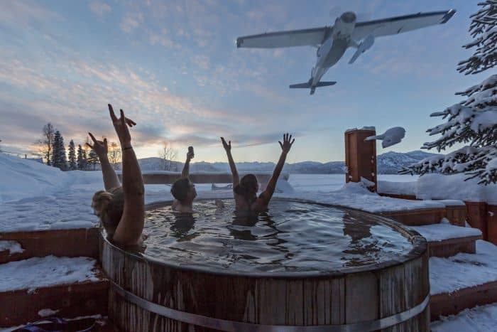 Guests at Tordrillo Mountain Lodge relax in the outdoor copper hot tub after a day of heli skiing.