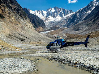 a helicopter sits in a valley within the tordrillo mountains after taking clients hiking