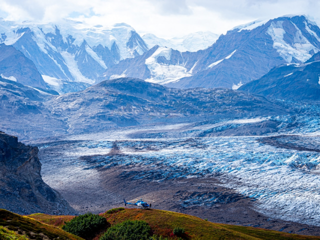 a helicopter with tordrillo mountain lodge parked over the trimble glacier