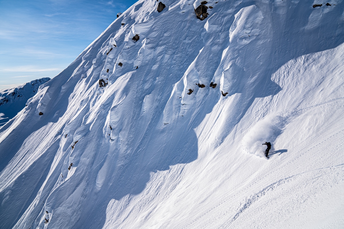 Heli snowboarder navigates a blanket of fresh mountain snow in Alaska.