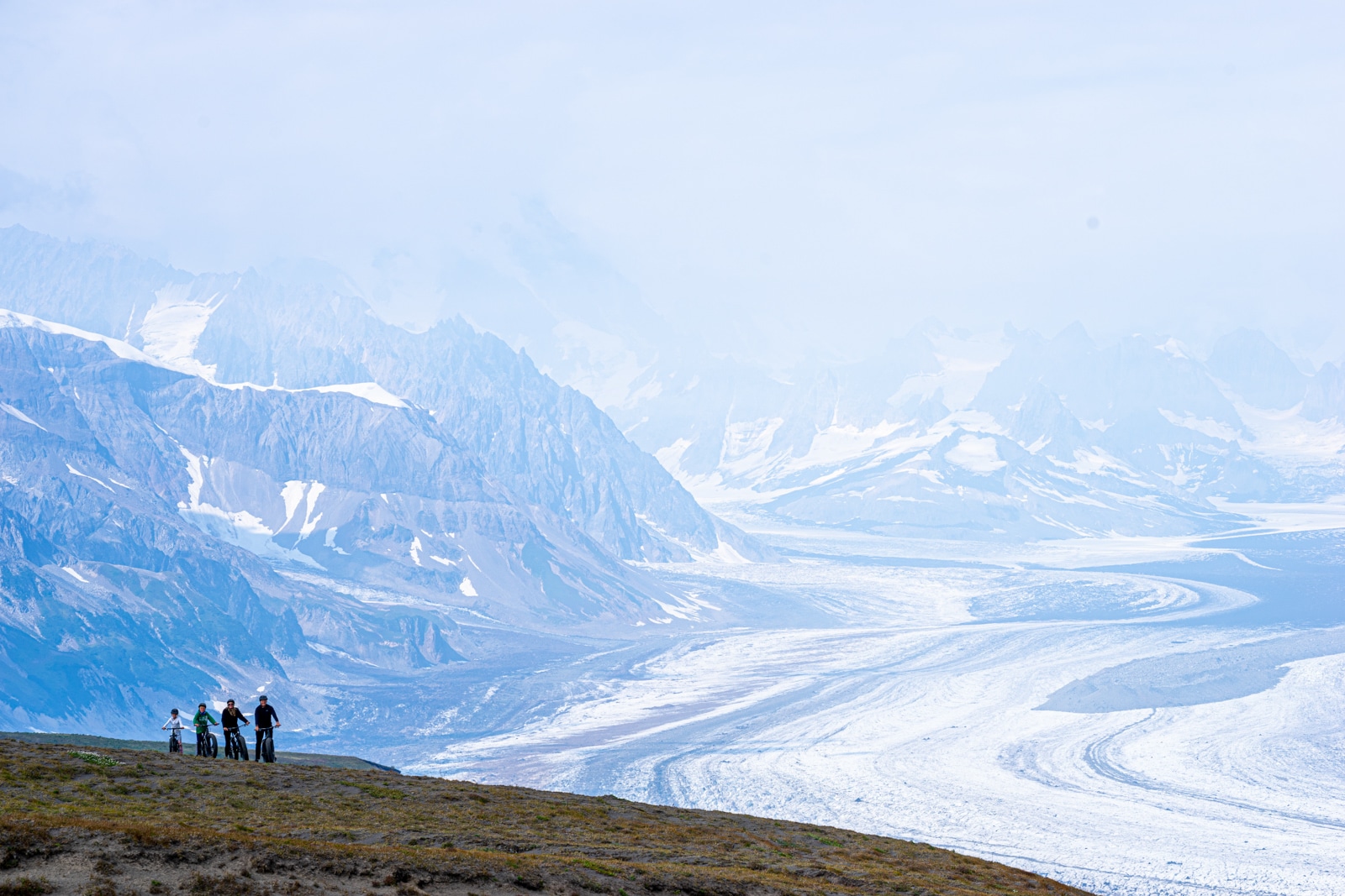 a family bikes over a glacier in the tordrillo mountains