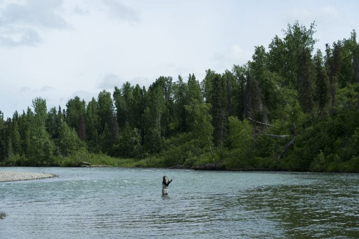 A lone angler fly fishes for salmon on a river near Tordrillo Mountain Lodge.