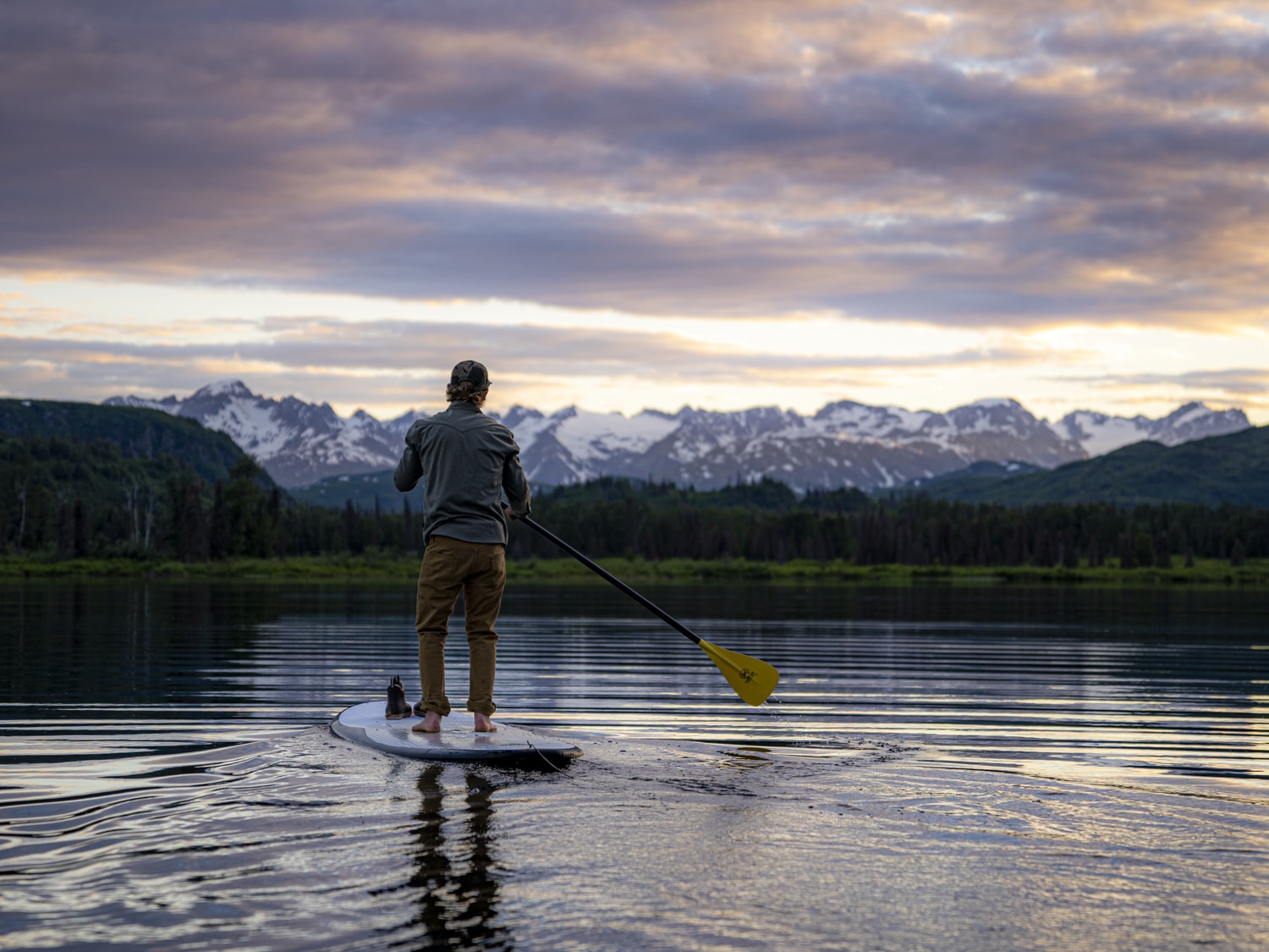 a man paddleboards across judd lake at sunset