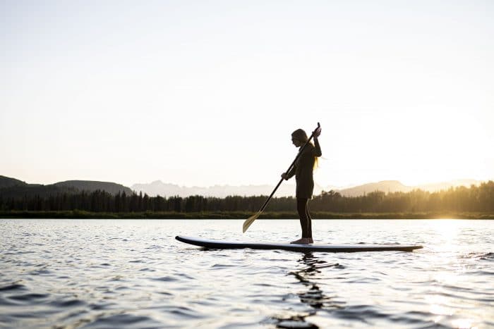 a woman paddleboarding at sunset on judd lake