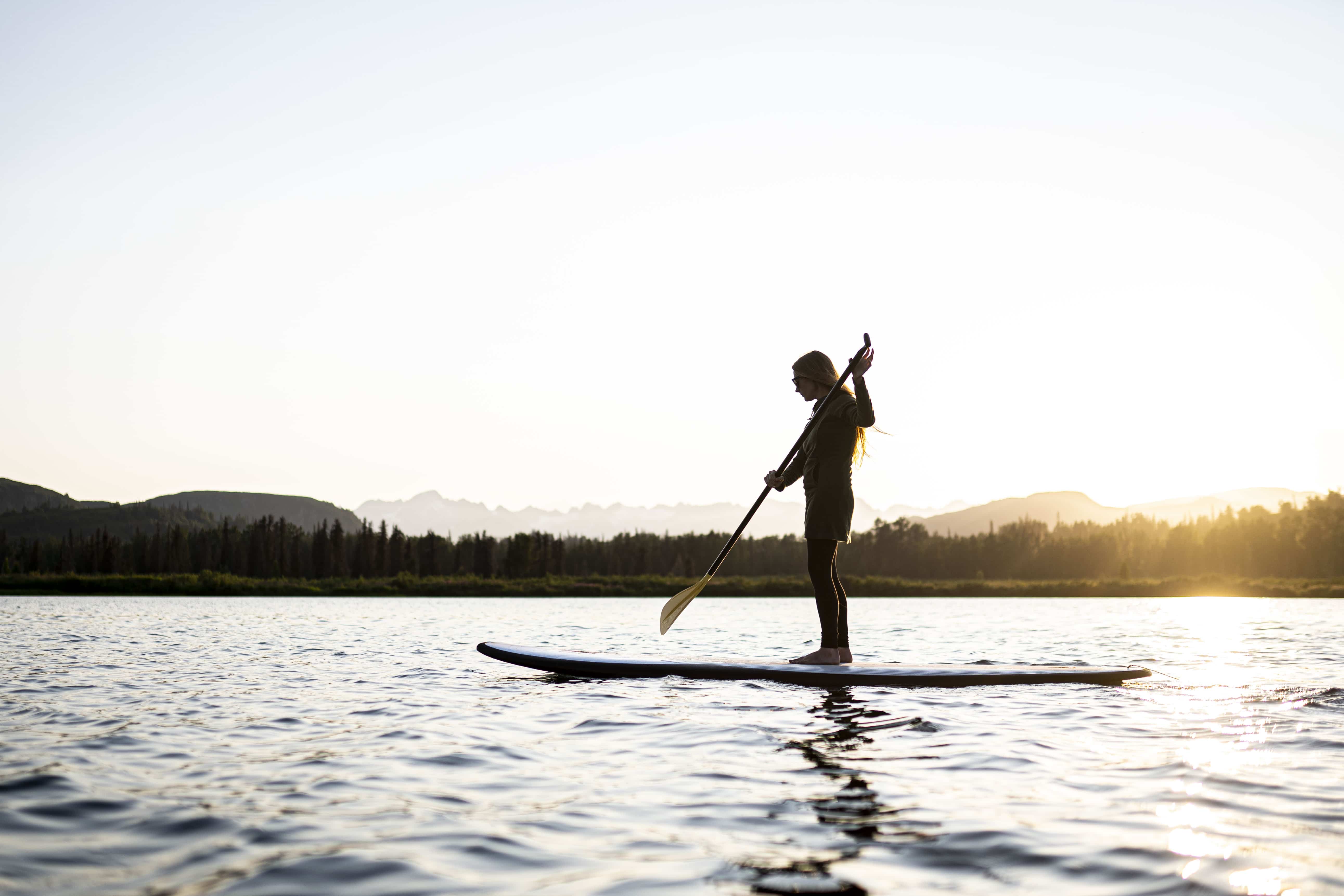 a woman paddleboarding at sunset on judd lake